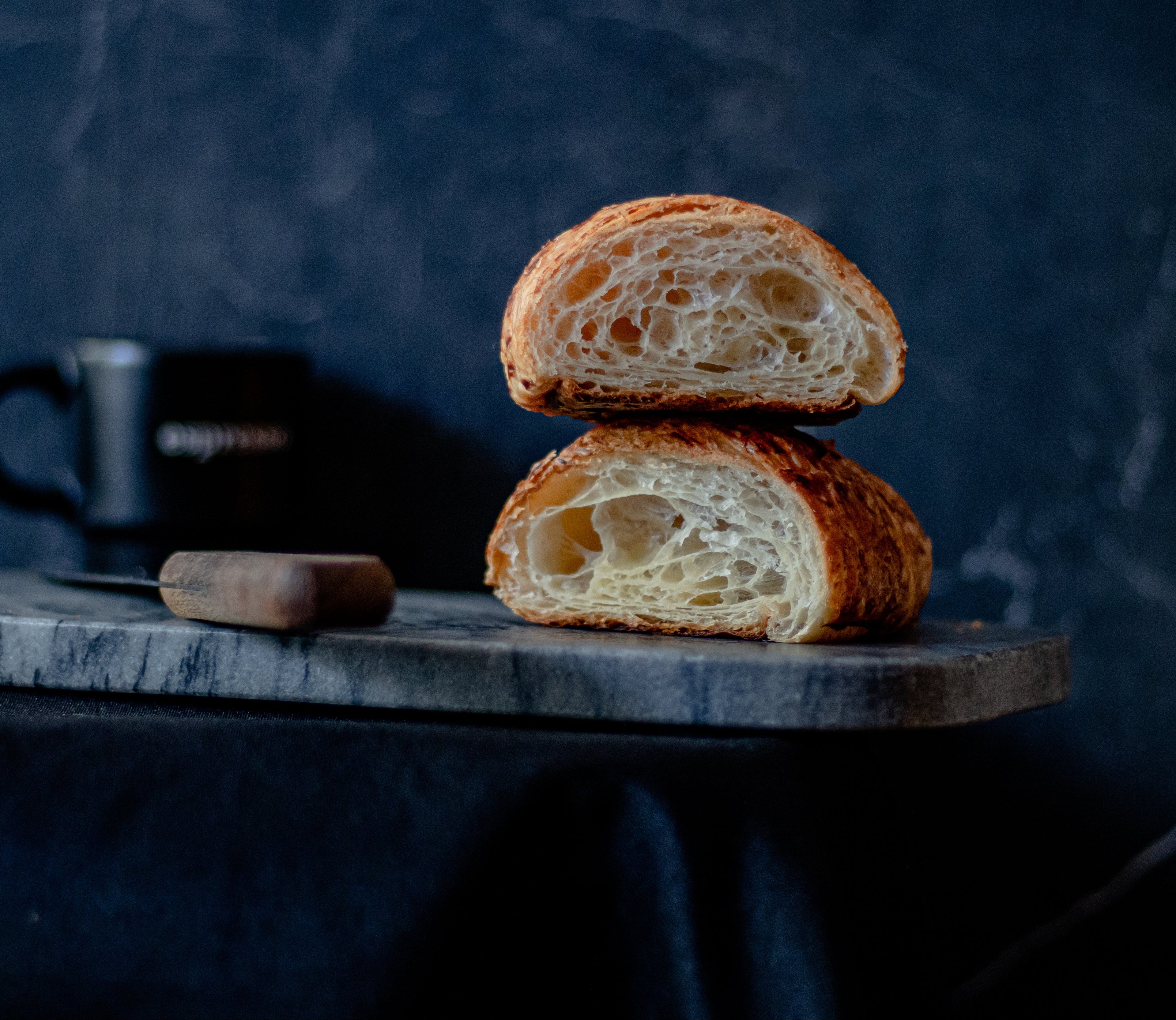 Two slices of bread stacked on a wooden board with a dark background